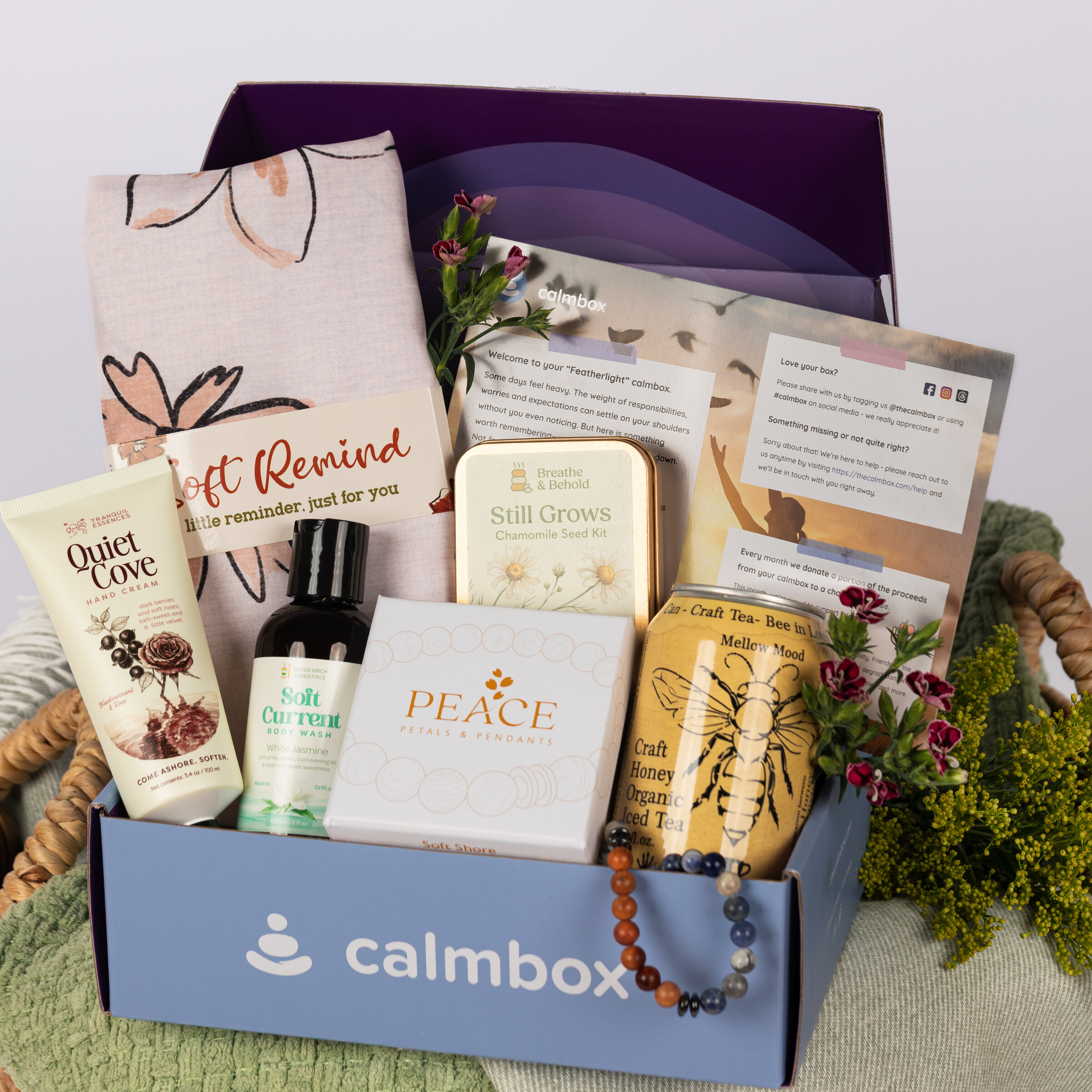 open calmbox in a basket with hand cream, a seed kit, a pendant and honey tea